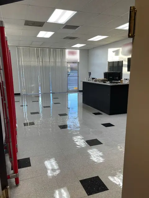 A glossy white tile floor set with black inset tiles in a lobby, with a black reception counter at the back